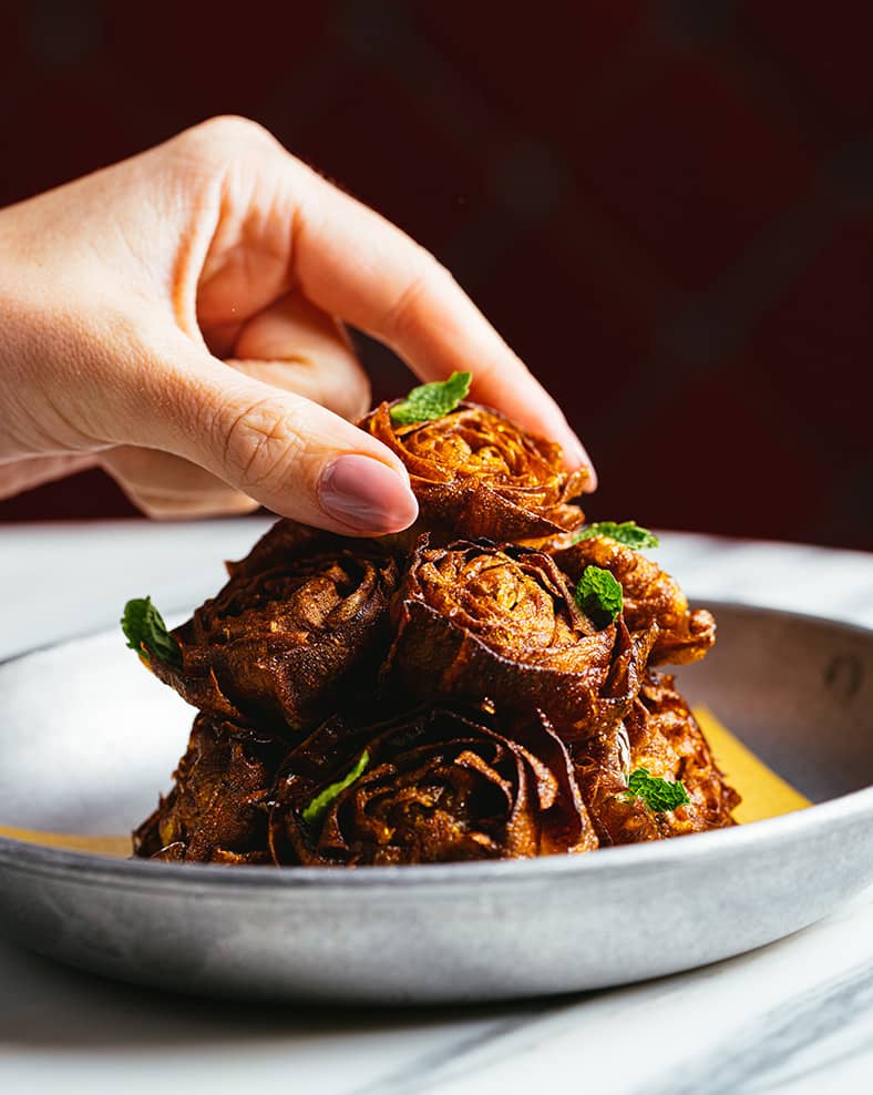 A hand grabbing food from a plate.