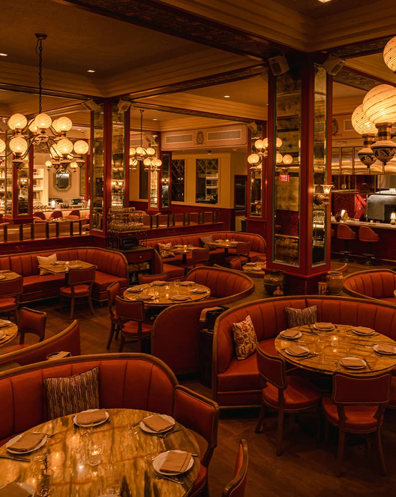 Mother Wolf interior, showing some circular tables in the front with a bar in the background.