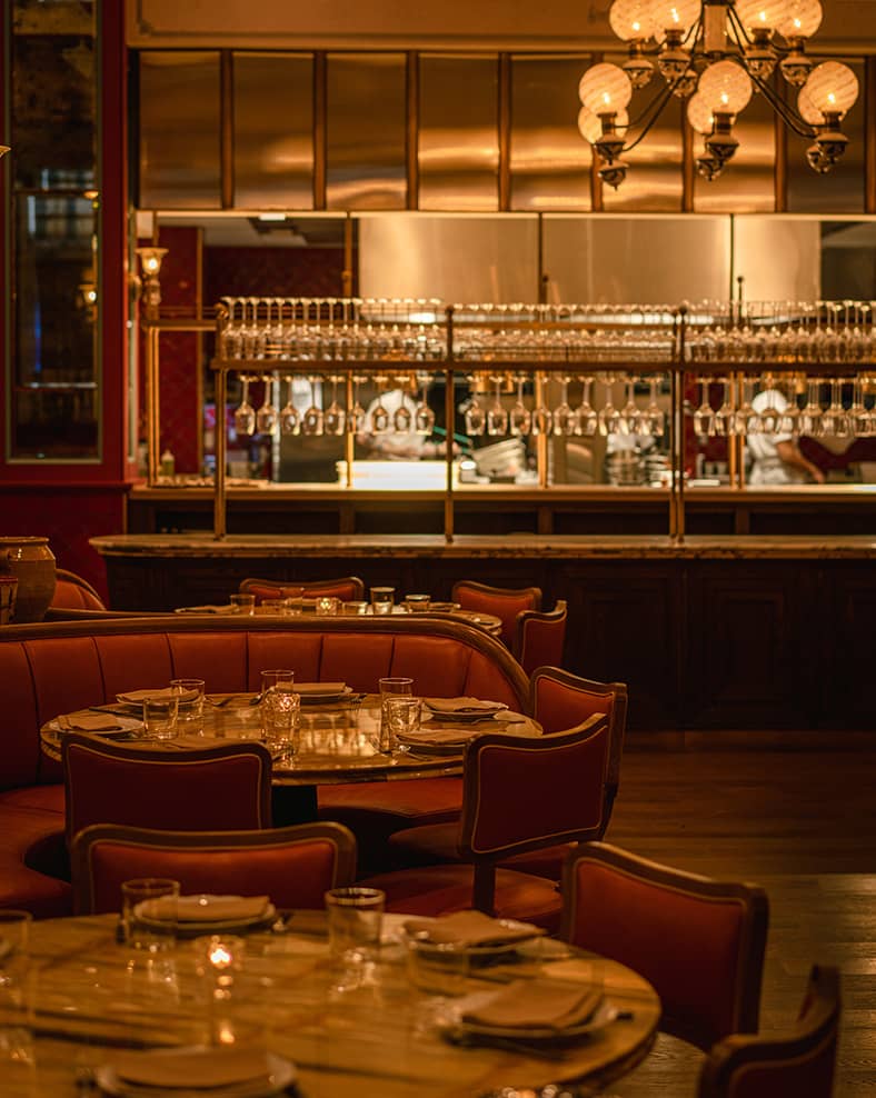 Mother Wolf interior, showing some circular tables in the front with a bar in the background.