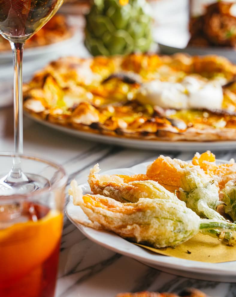 Macro shot of a table with various Italian foods and cocktails.