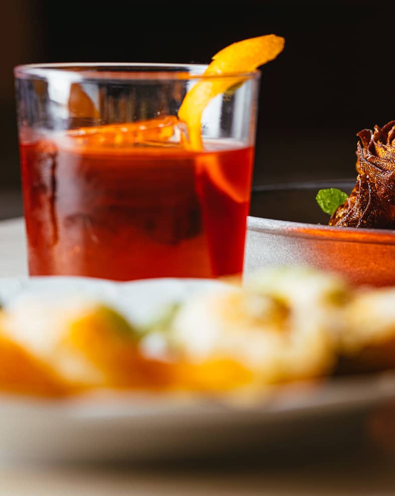 Macro shot of a table with a drink and plates of food.