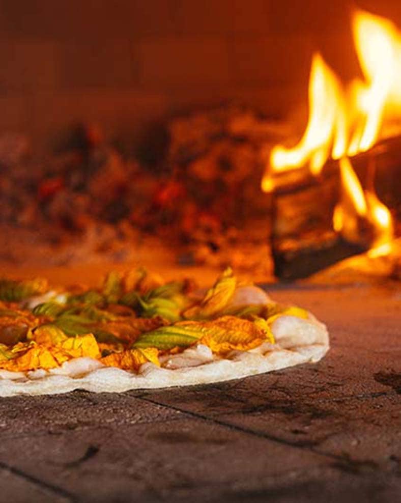 Pizza being cooked in a wood-fired oven.