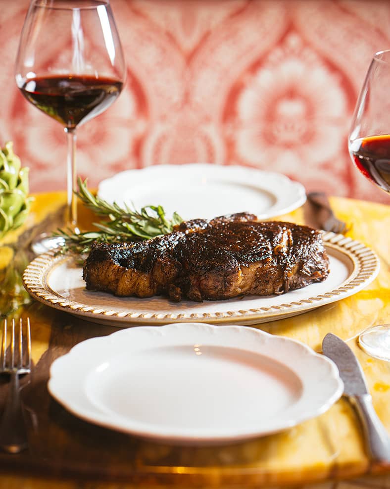 A plate of meat with glasses of red wine.